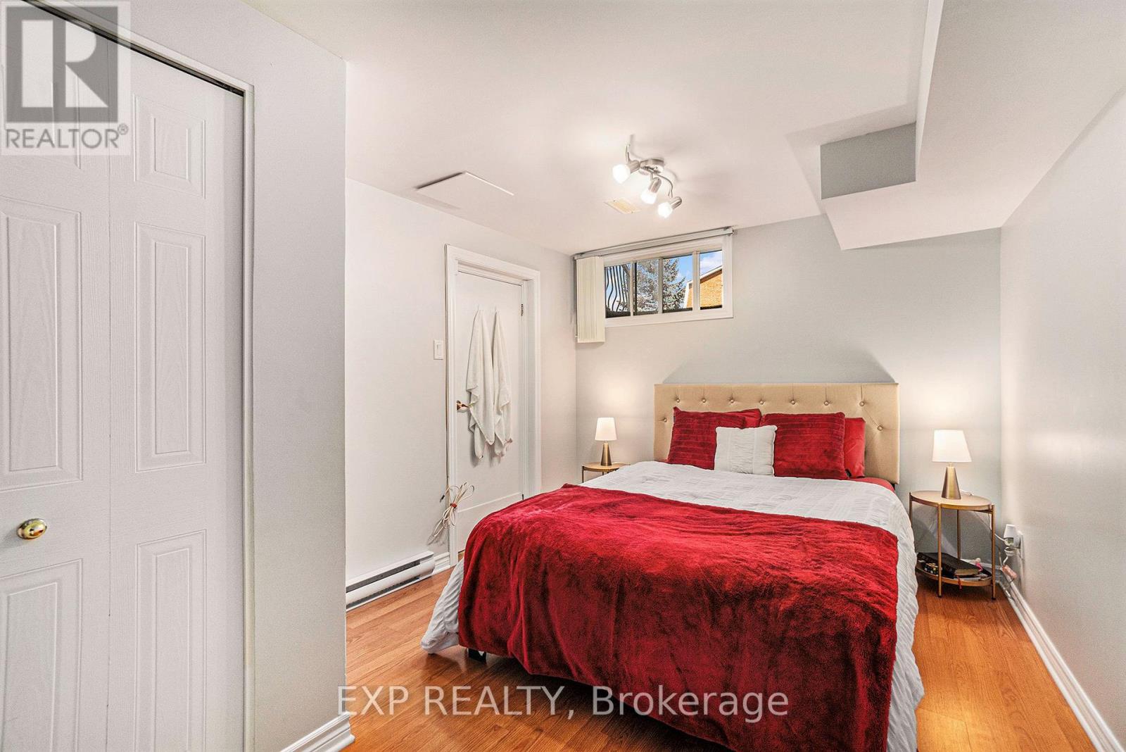 A bedroom with a red bedspread and a white door.