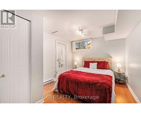 A bedroom with a red bedspread and a white door.