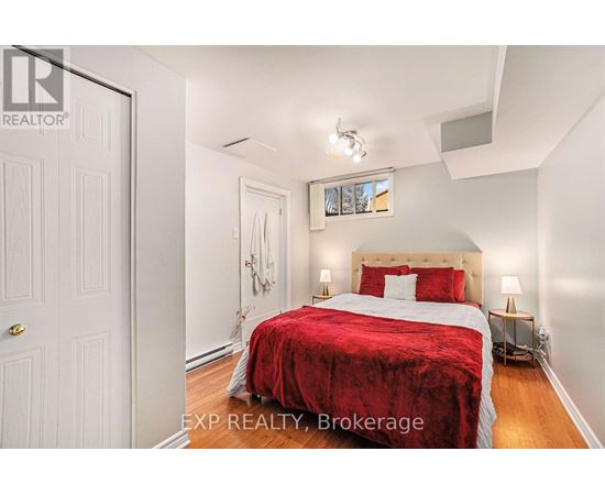 A bedroom with a red bedspread and a white door.