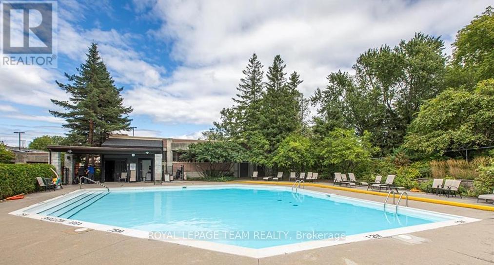 A pool surrounded by trees and a building in the background.
