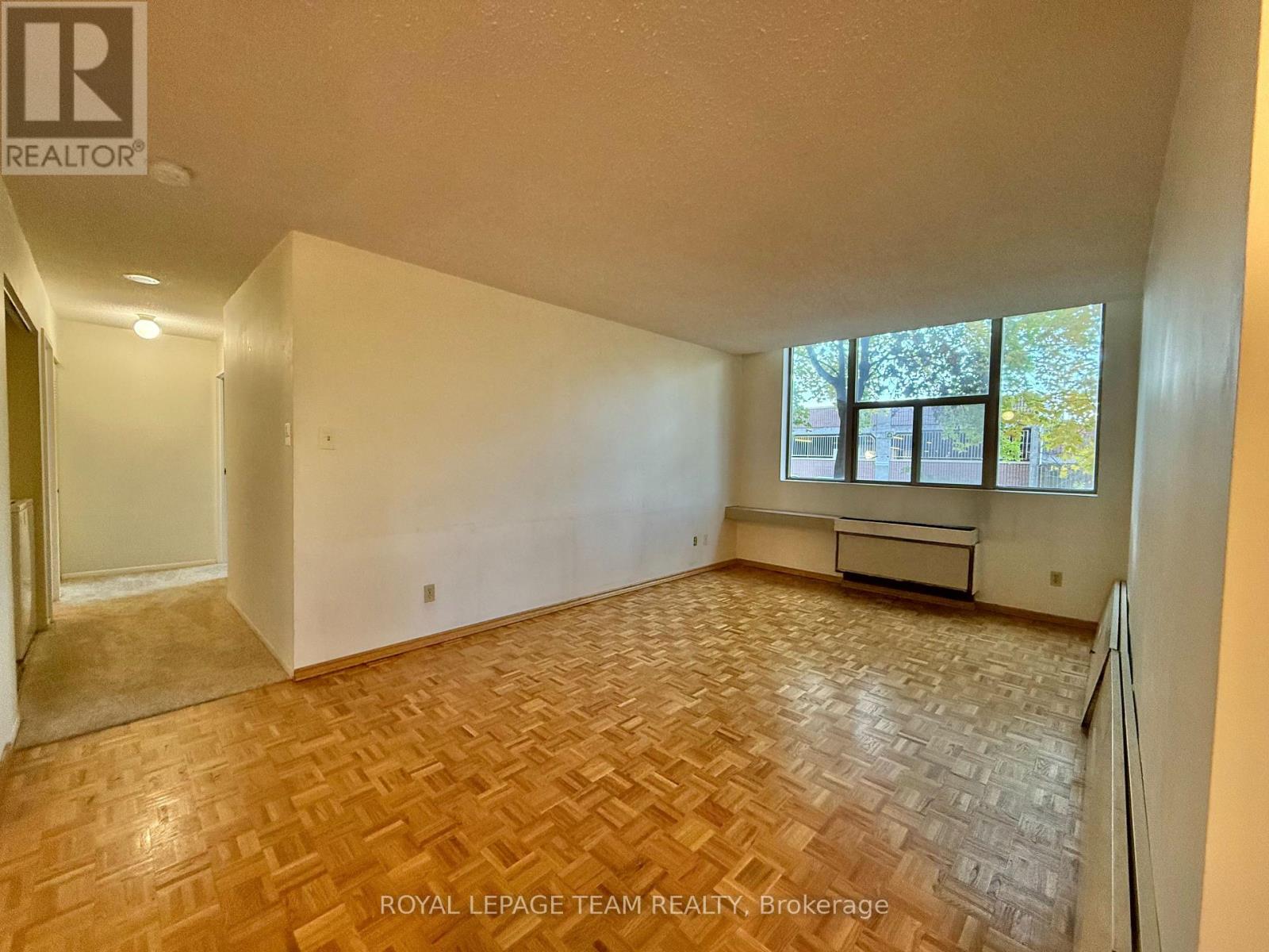 A room with a wooden floor and a window with a view of trees.