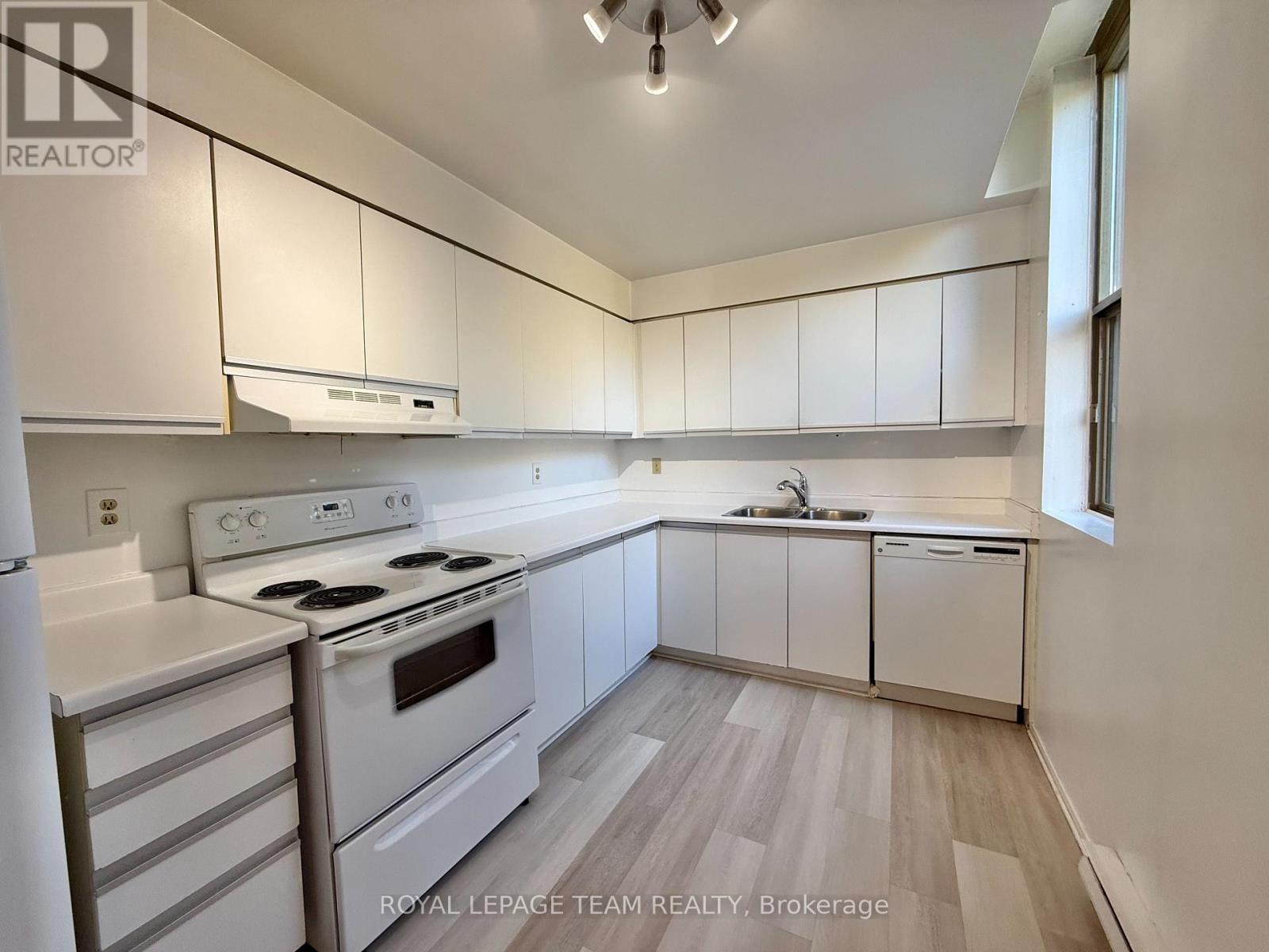A white kitchen with a stove, oven, and sink.
