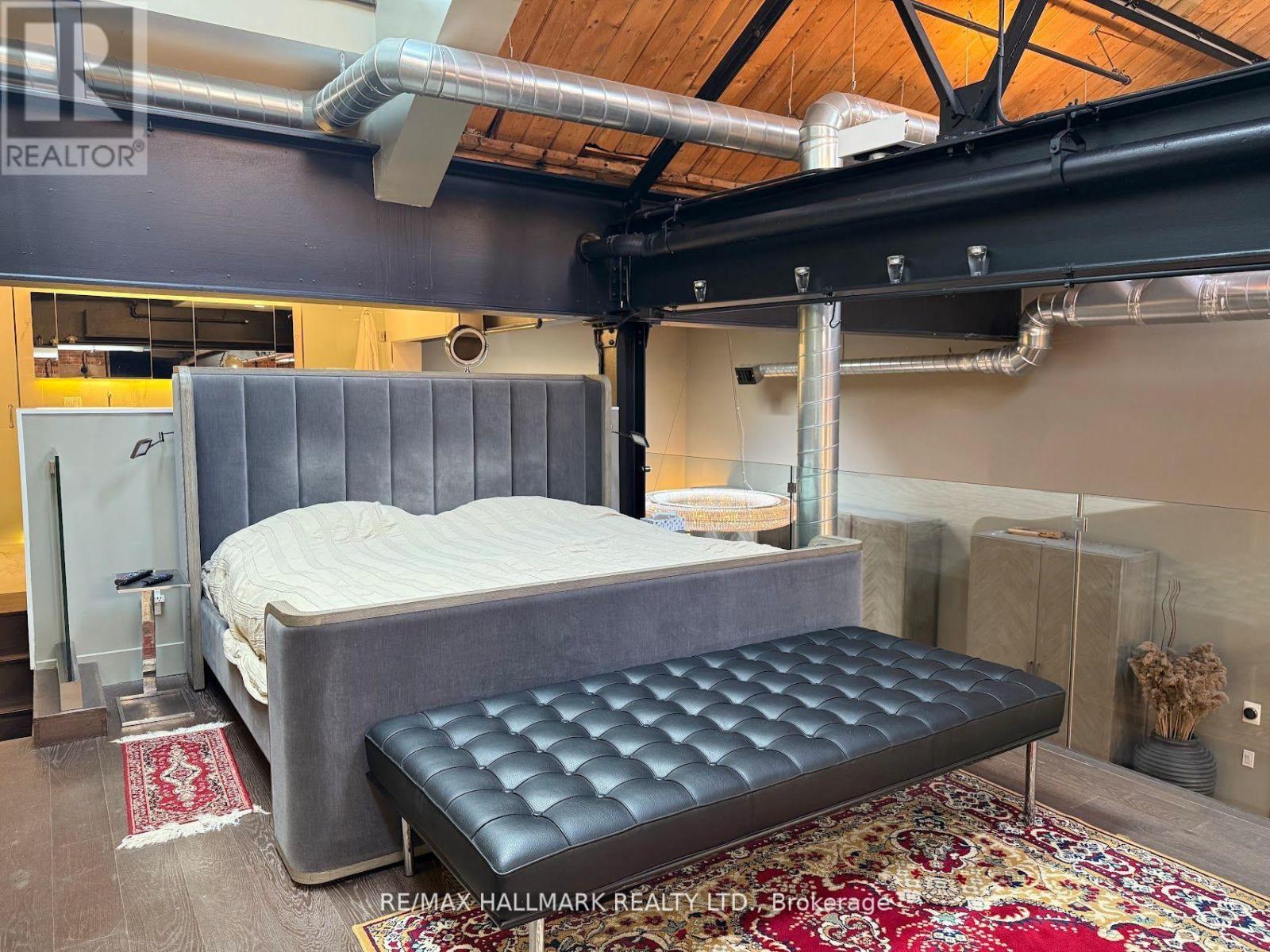 A bedroom with a bed and a bench in the middle of the room.