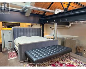 A bedroom with a bed and a bench in the middle of the room.