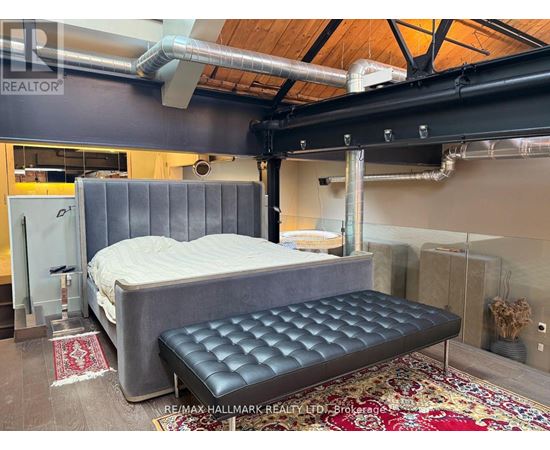 A bedroom with a bed and a bench in the middle of the room.