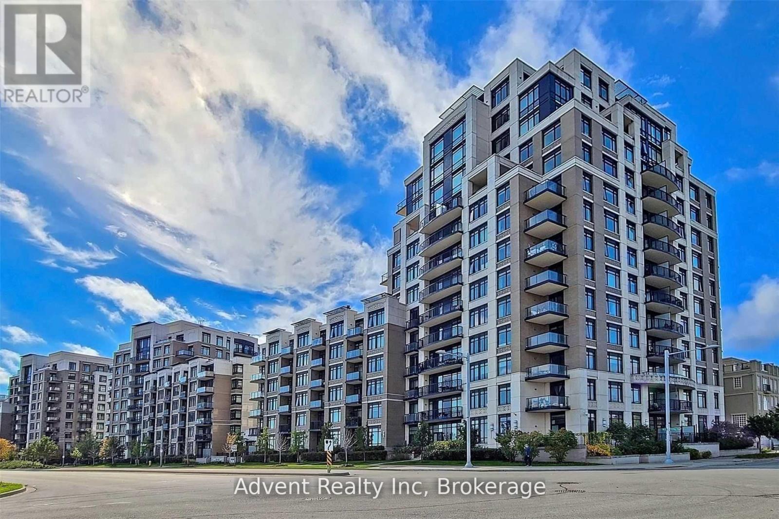 A large apartment building with a clear blue sky and some clouds in the background.