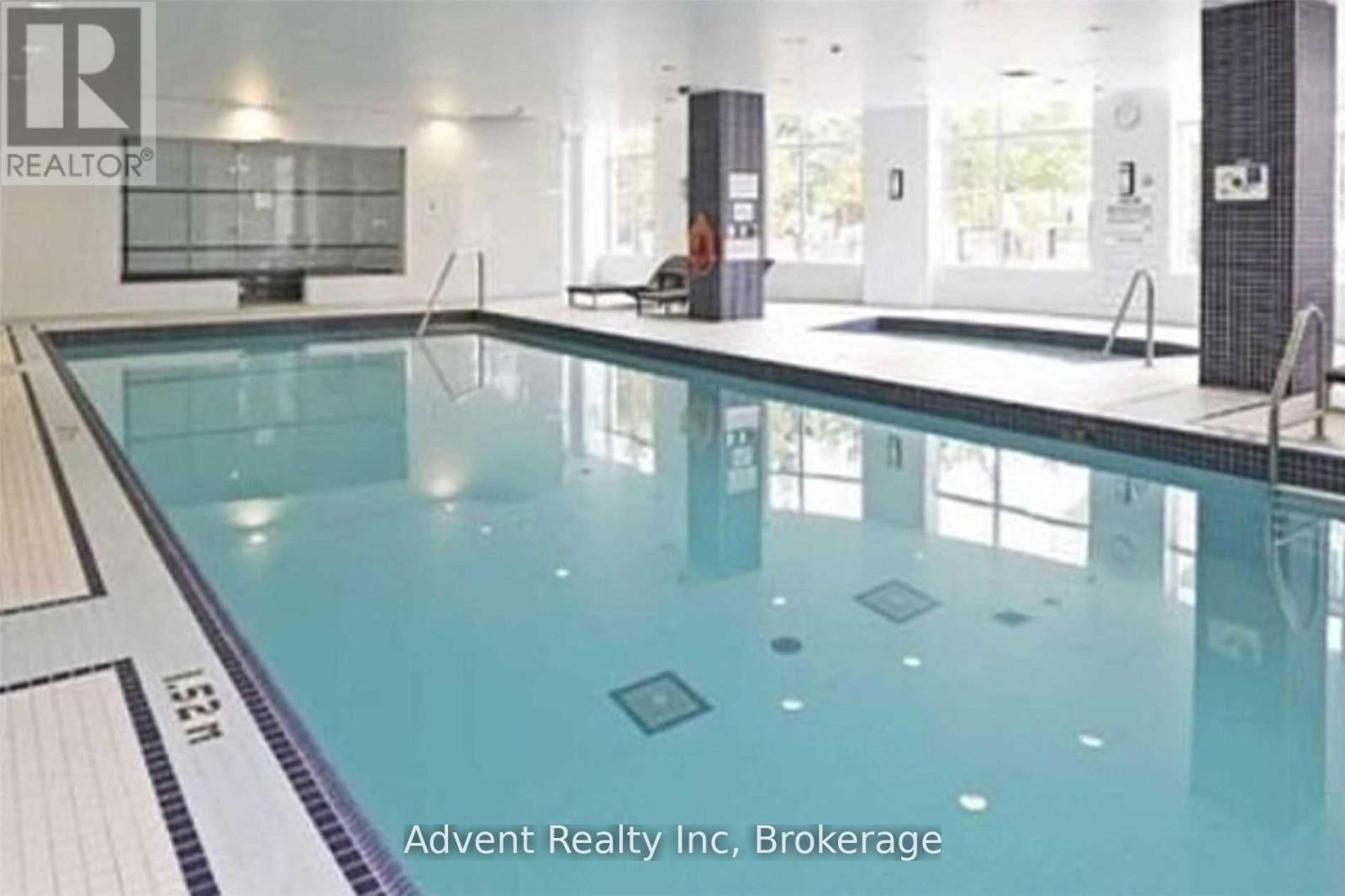 A swimming pool inside a building with the logo of Advent Realty Inc, Brokerage.