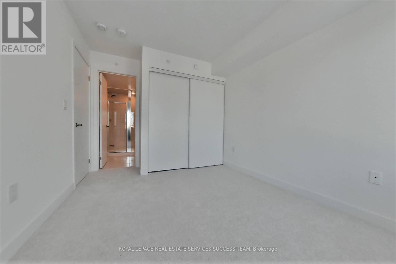 A white bedroom with a door and a hallway.