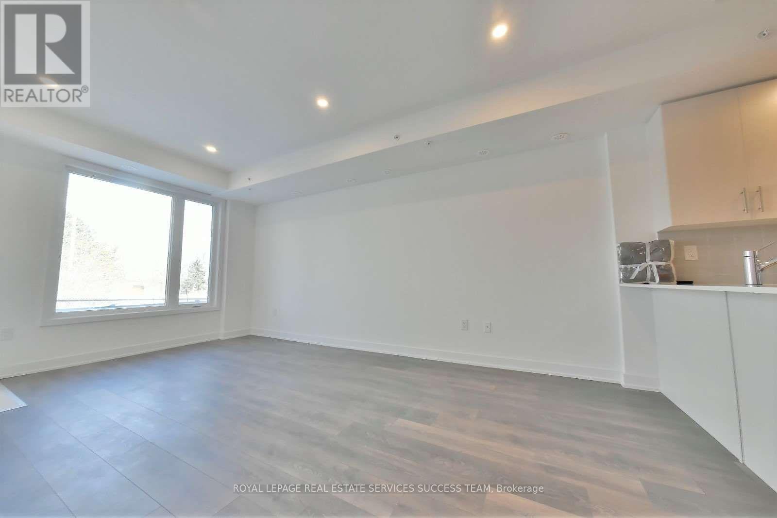 A spacious room with wooden flooring and white walls.
