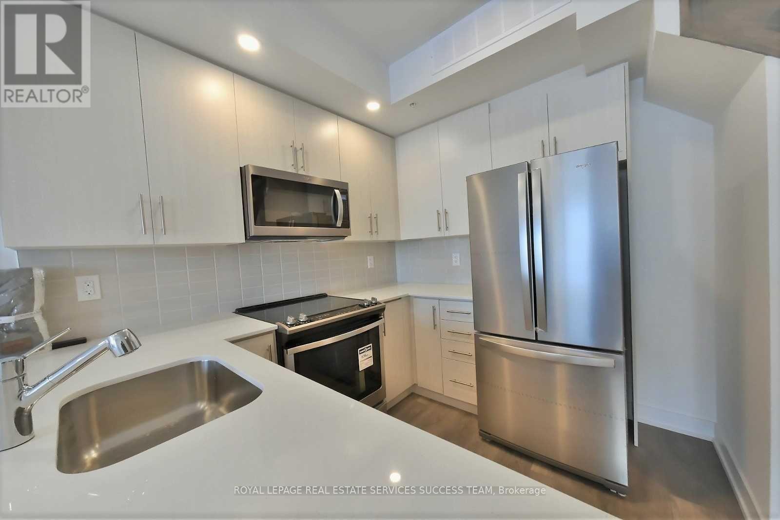 A kitchen with a stainless steel refrigerator and microwave above the sink.