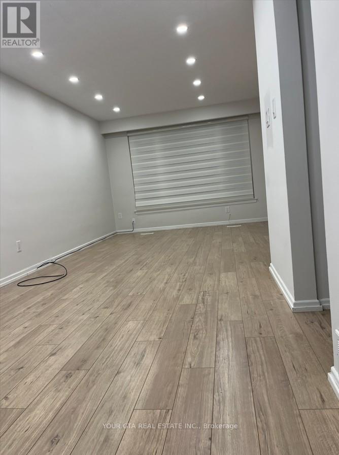 A room with wooden flooring and a roller shutter door.