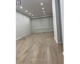 A room with wooden flooring and a roller shutter door.