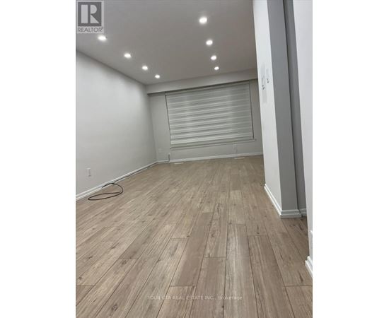 A room with wooden flooring and a roller shutter door.