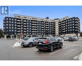 A black and white apartment building with cars parked in front.