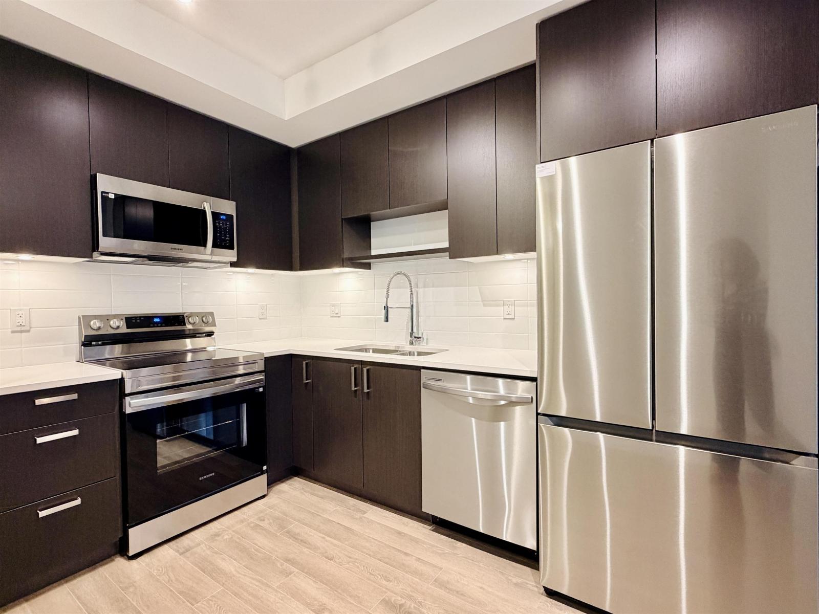 A modern kitchen with dark brown cabinets and stainless steel appliances.