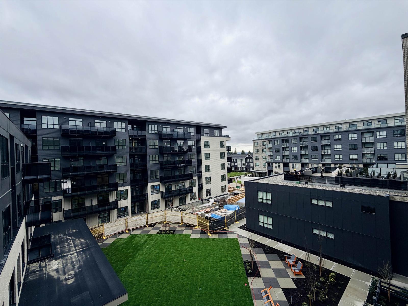 A modern building complex with a green lawn in the foreground.