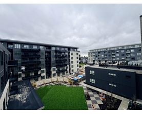 A modern building complex with a green lawn in the foreground.