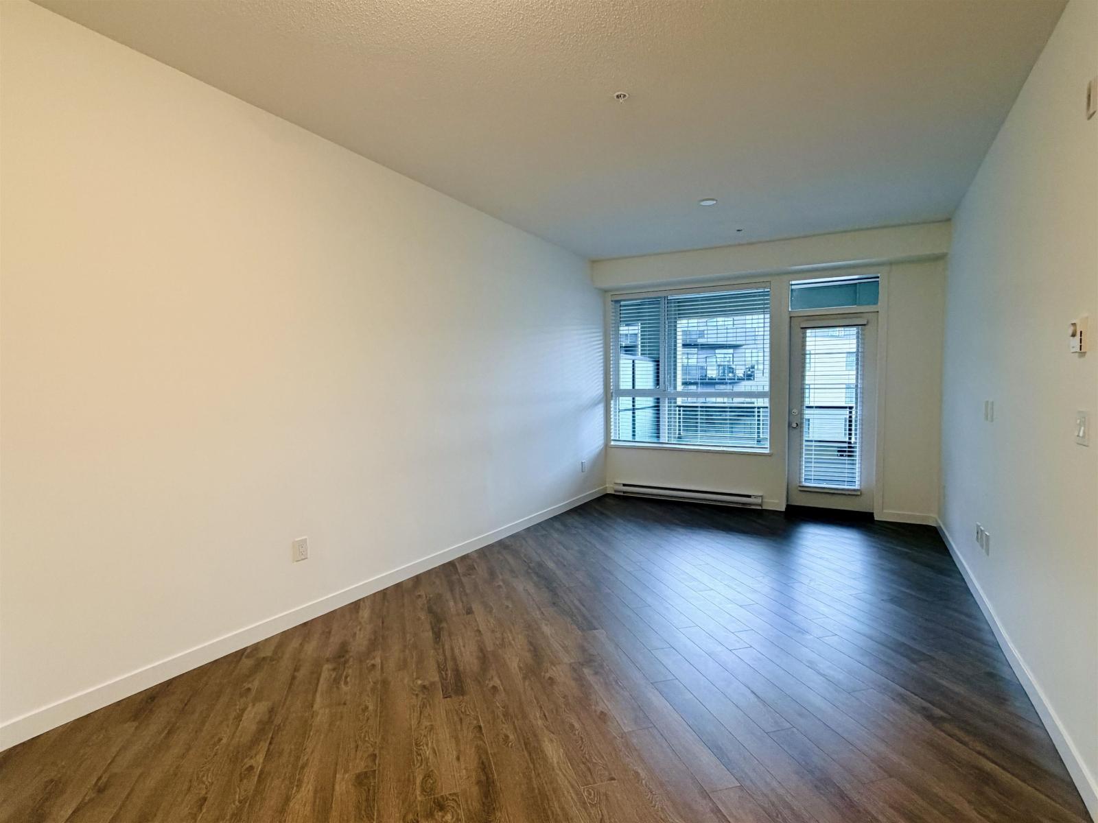 A room with wooden flooring and a window with blinds.