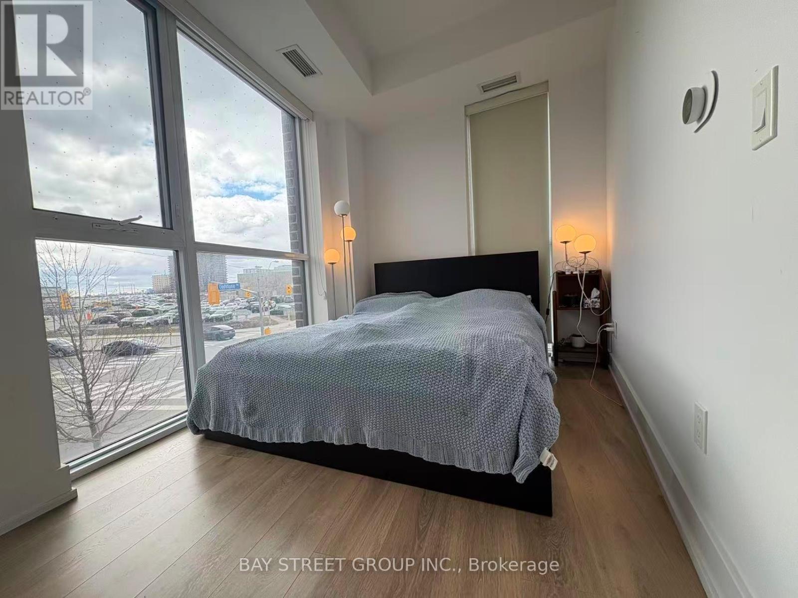 A bedroom with a large bed and a view of the city through the window.