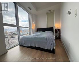 A bedroom with a large bed and a view of the city through the window.
