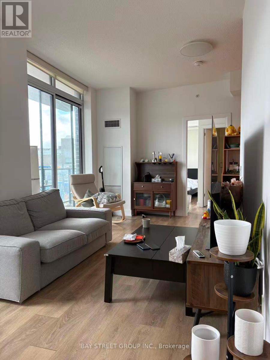 A living room with a grey couch, a black coffee table, and a wooden side table with a plant on it.
