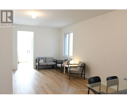 A living room with a couch, chairs, and a dining table.