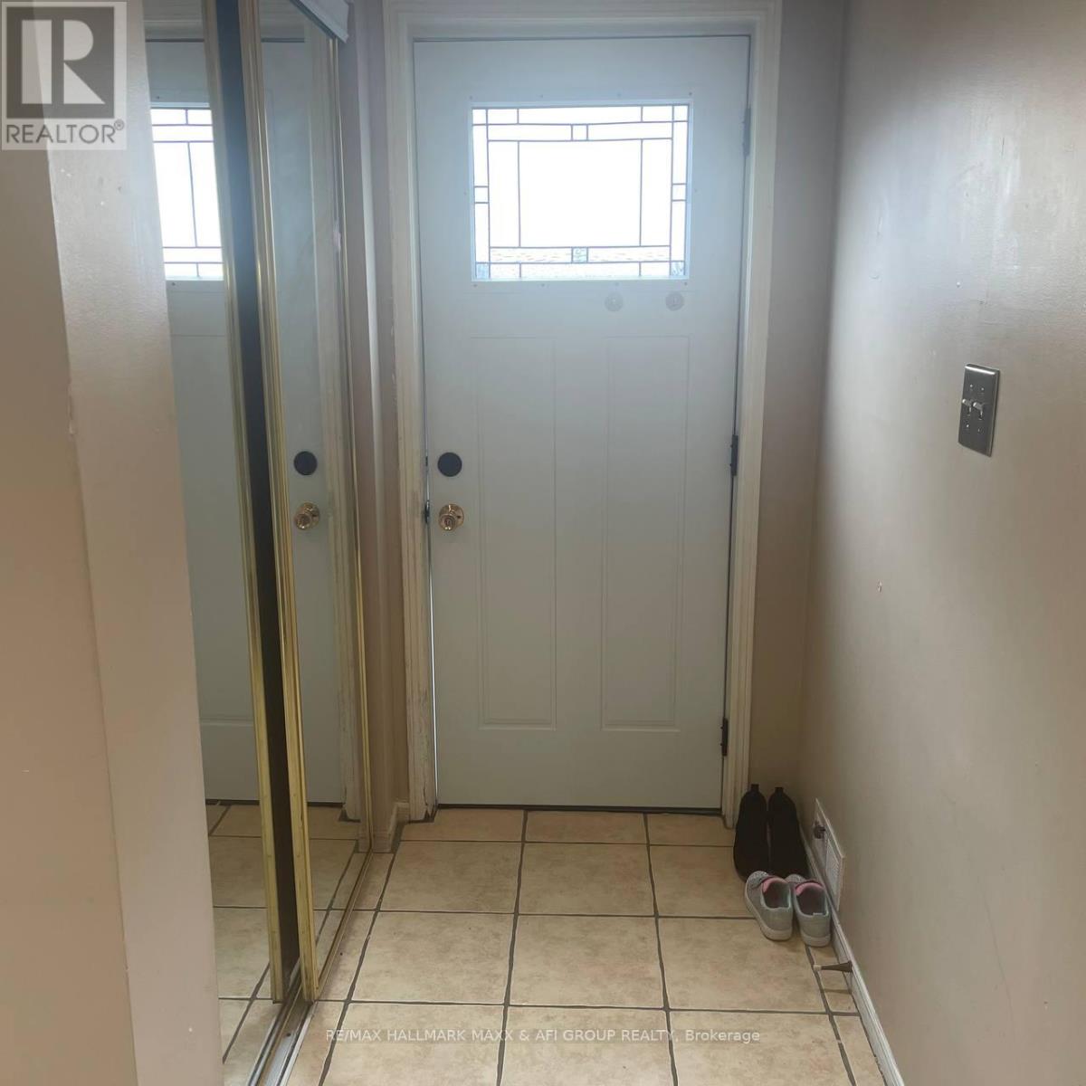 A white door with a window above it and a pair of shoes on the floor.
