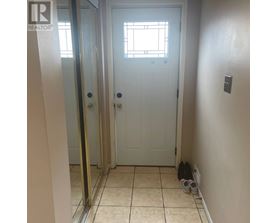 A white door with a window above it and a pair of shoes on the floor.