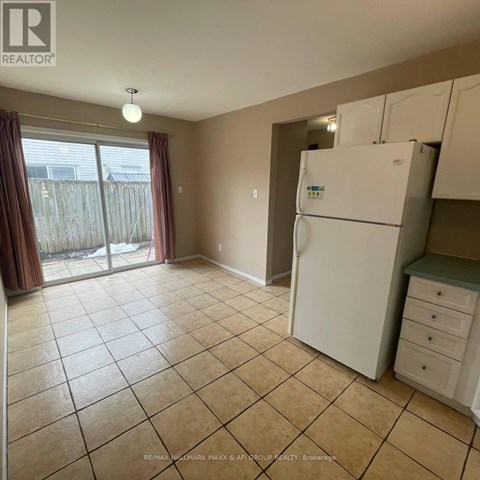 A white refrigerator is in a kitchen with tile flooring.