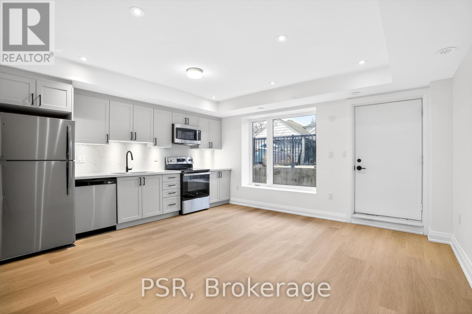 A spacious kitchen with wooden floors and white walls.