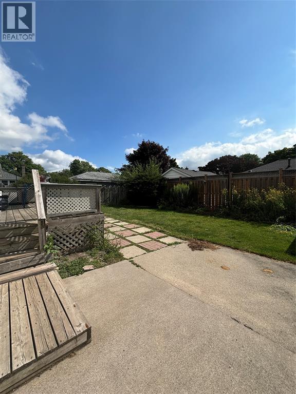 A backyard with a wooden deck and a paved walkway.