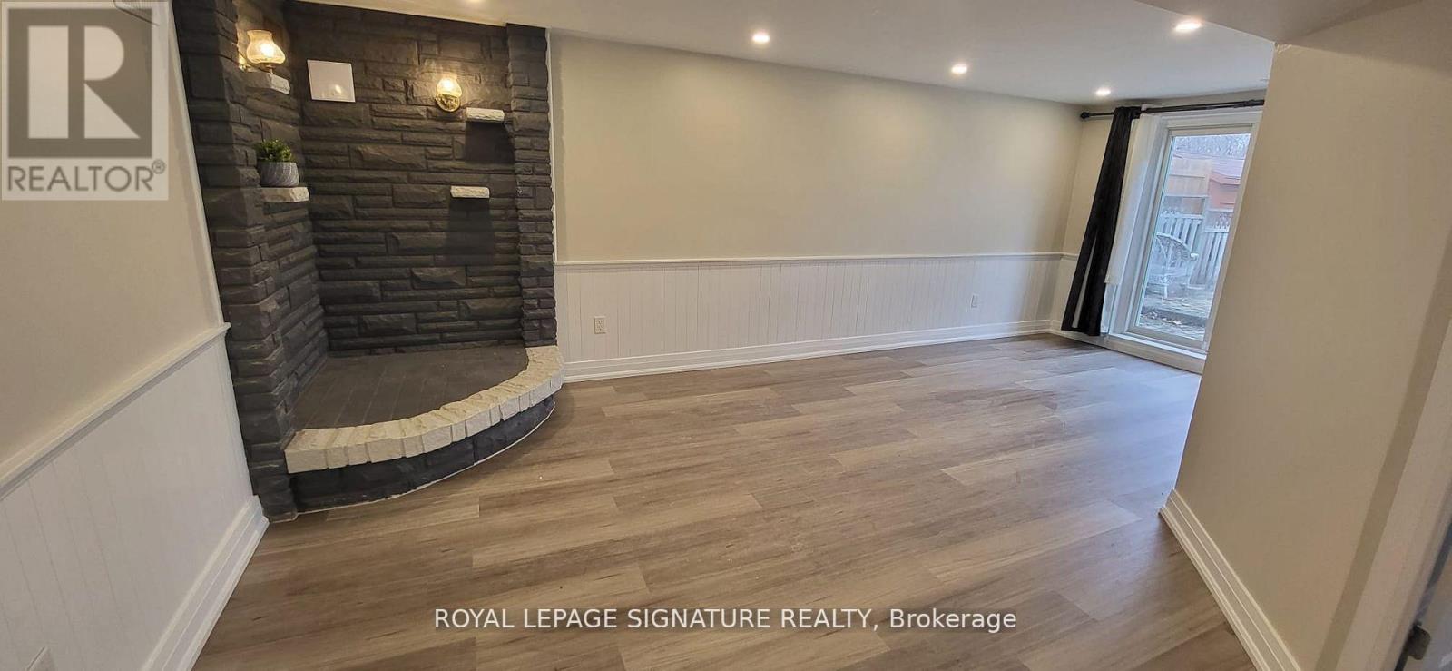 A room with a fireplace and wooden flooring.