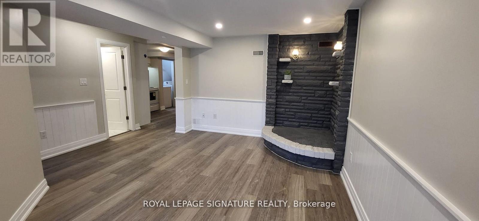 A spacious room with wooden flooring and a black brick wall.