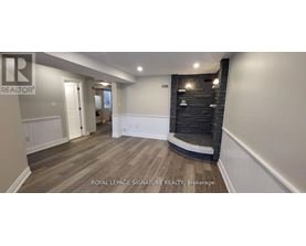 A spacious room with wooden flooring and a black brick wall.