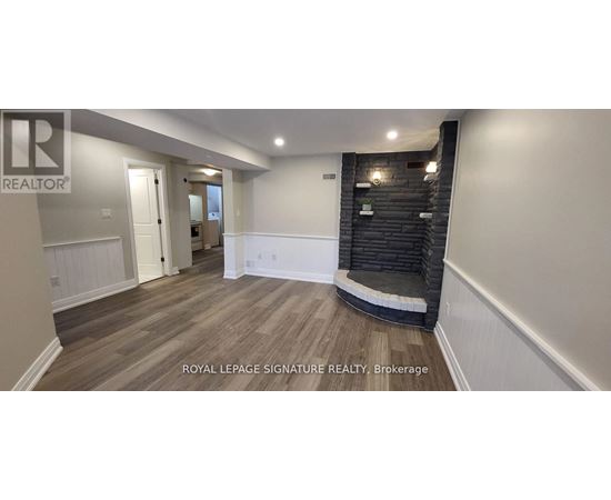 A spacious room with wooden flooring and a black brick wall.