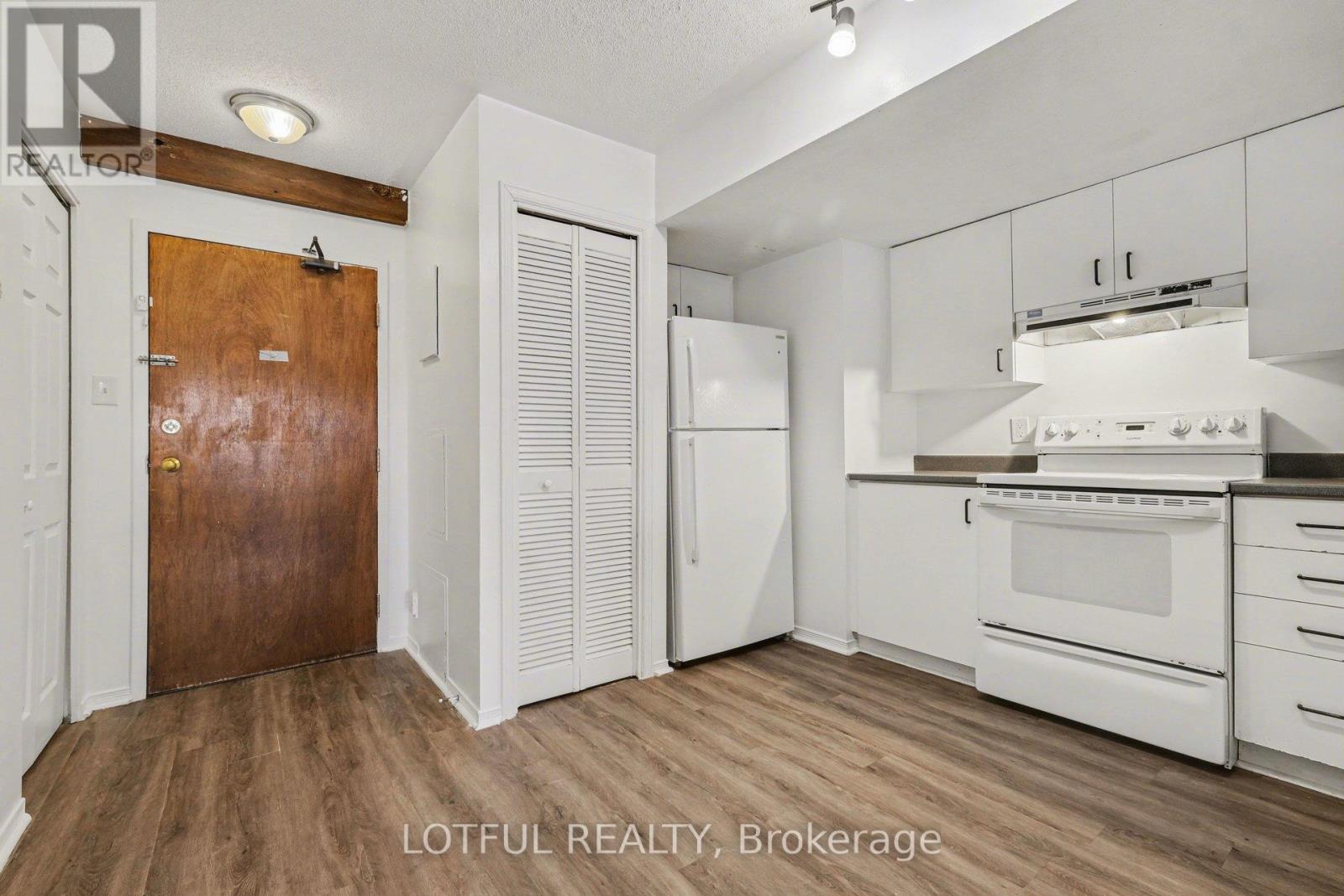 A kitchen with white cabinets and a wooden door.