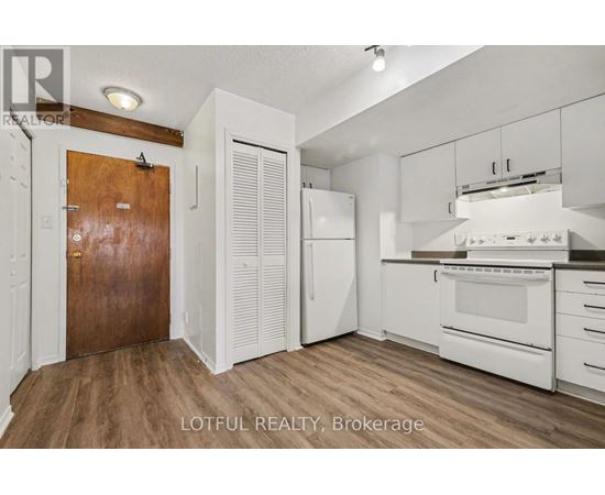 A kitchen with white cabinets and a wooden door.