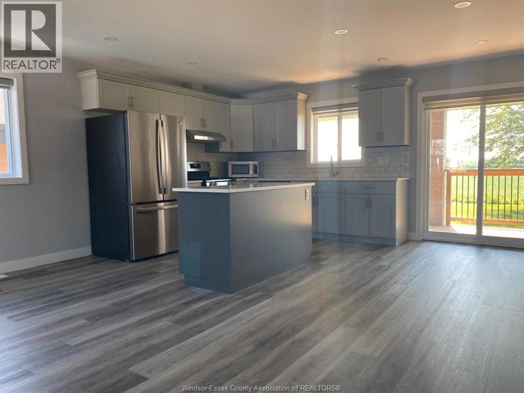 A kitchen with a refrigerator, microwave, and oven.