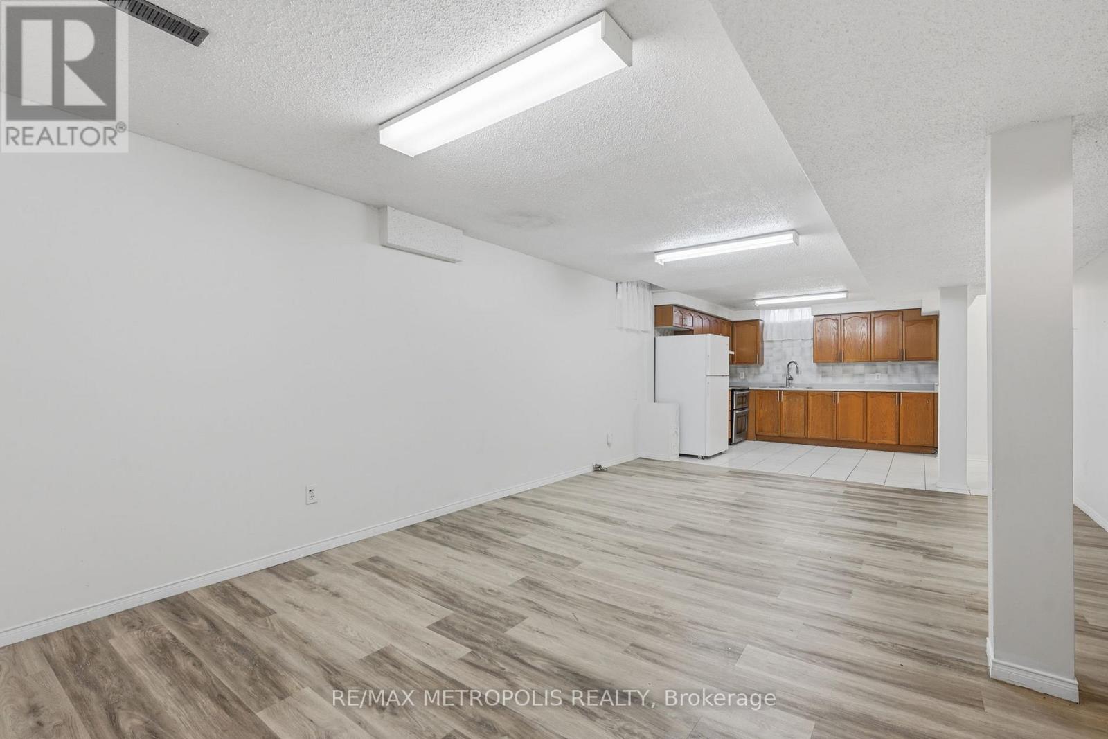A spacious room with wooden flooring and white walls.