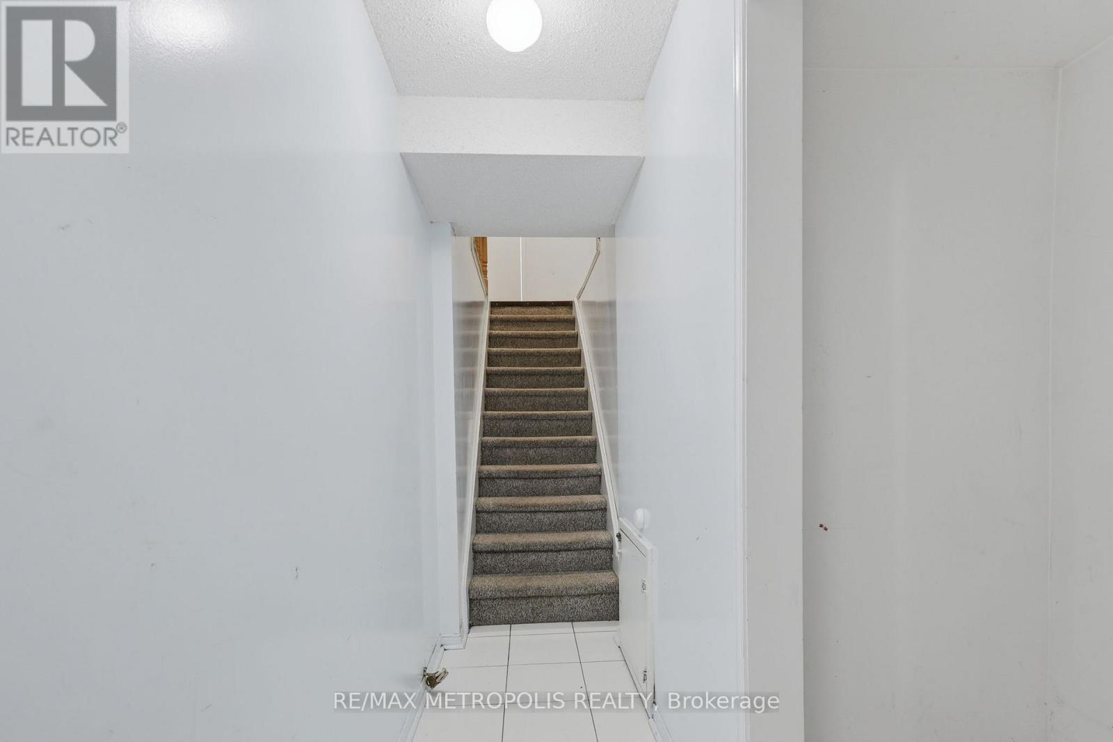 A staircase in a white hallway with a logo on the wall.