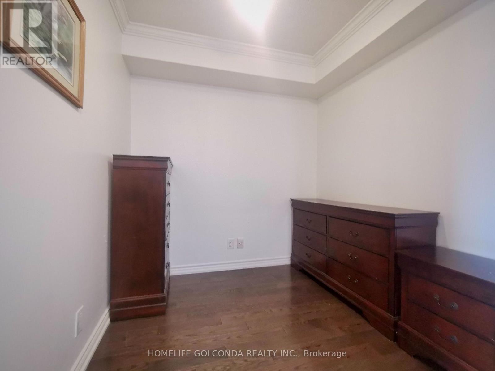 A bedroom with a wooden dresser and a wooden cabinet.