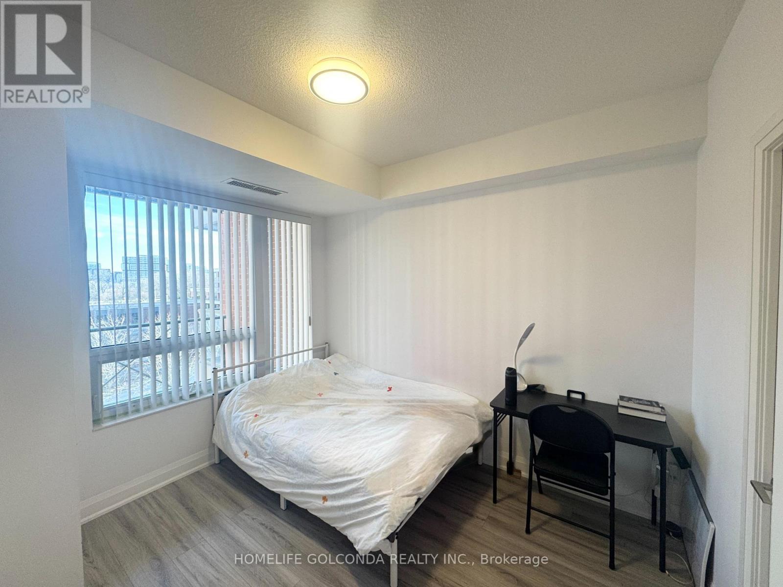 A bedroom with a bed, desk, and chair.