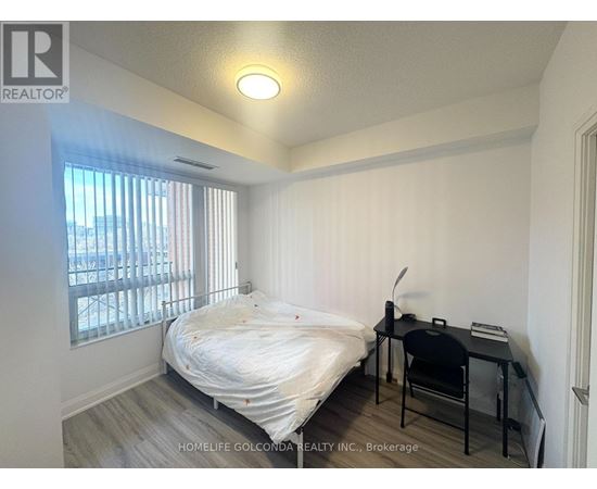 A bedroom with a bed, desk, and chair.