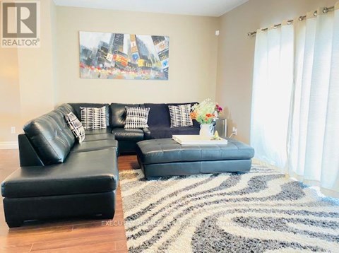 A living room with a black leather couch and ottoman.