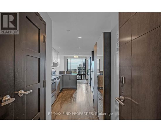 A modern kitchen with black cabinets and a blue rug on the floor.