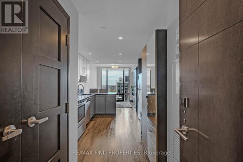 A modern kitchen with black cabinets and a blue rug on the floor.