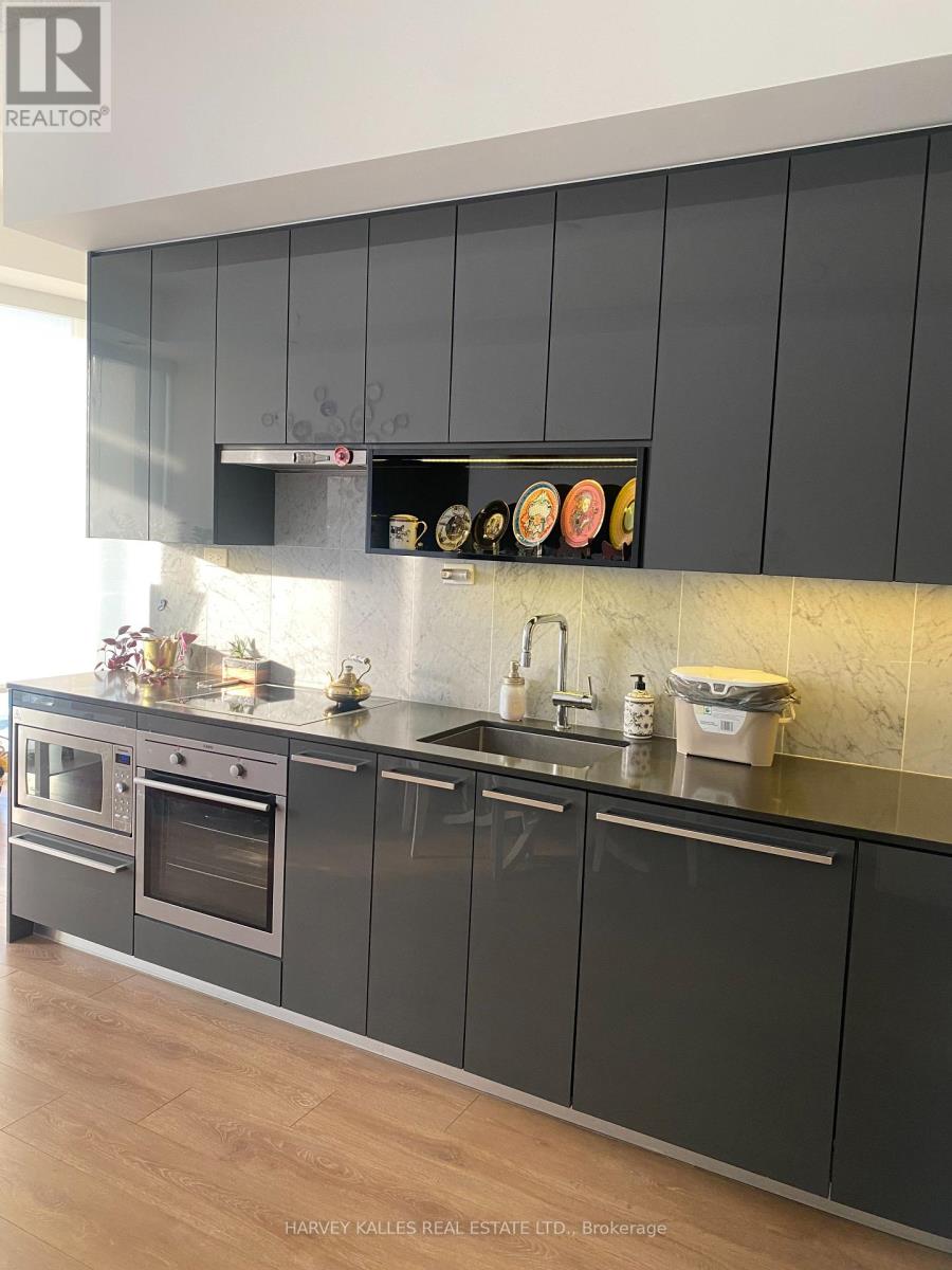 A modern kitchen with dark grey cabinets and a wooden floor.