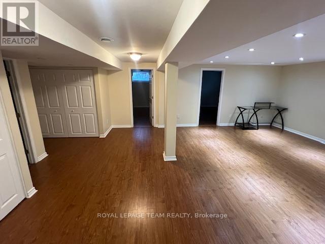 A spacious room with wooden flooring and white walls, with a door at the end of the hallway.