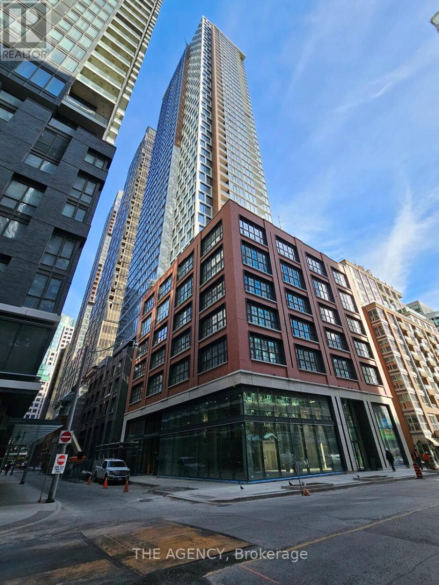 A tall building with a glass facade stands in front of a shorter building with a brick facade.