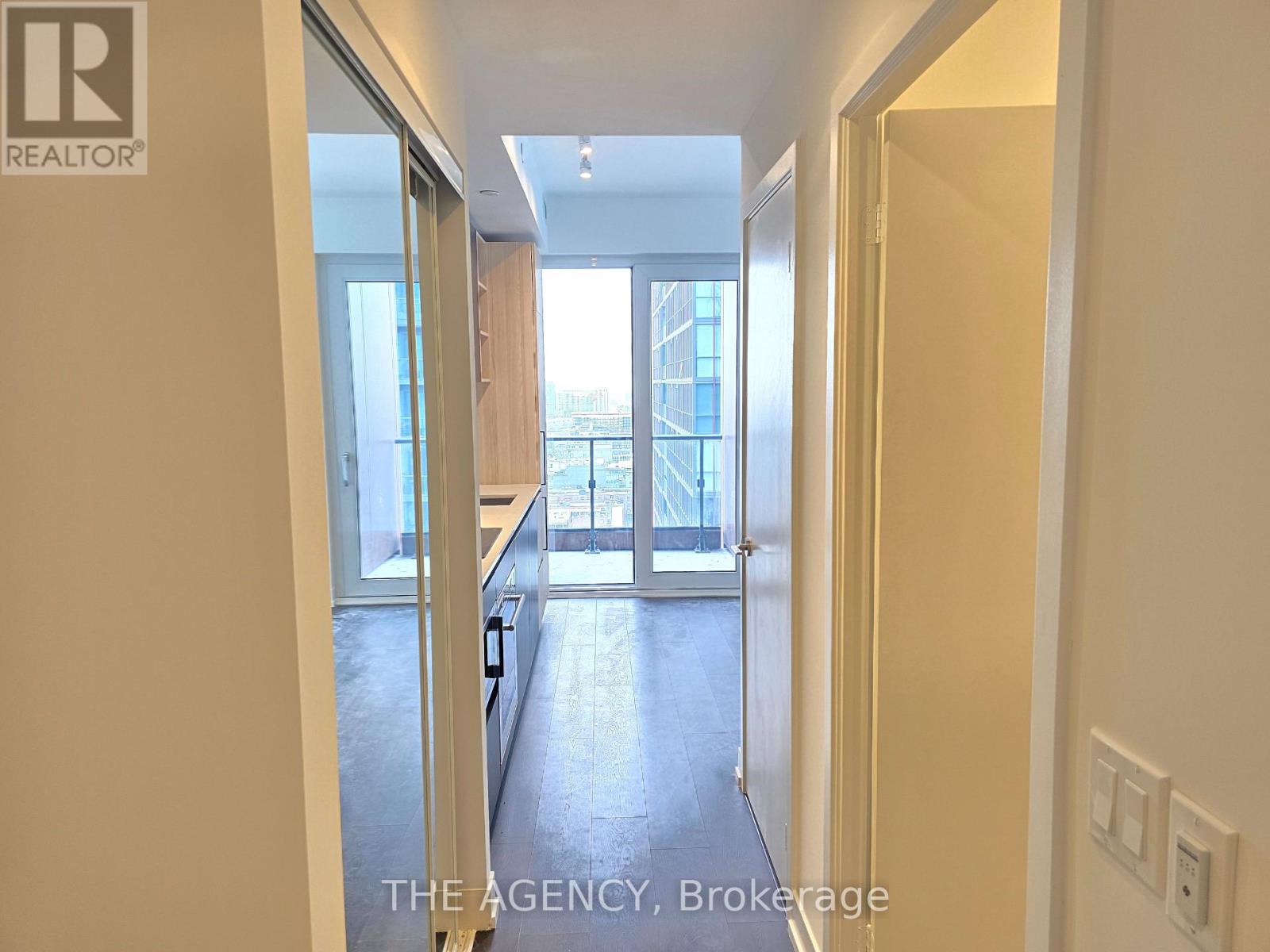 A hallway with a door on the right and a balcony in the distance.
